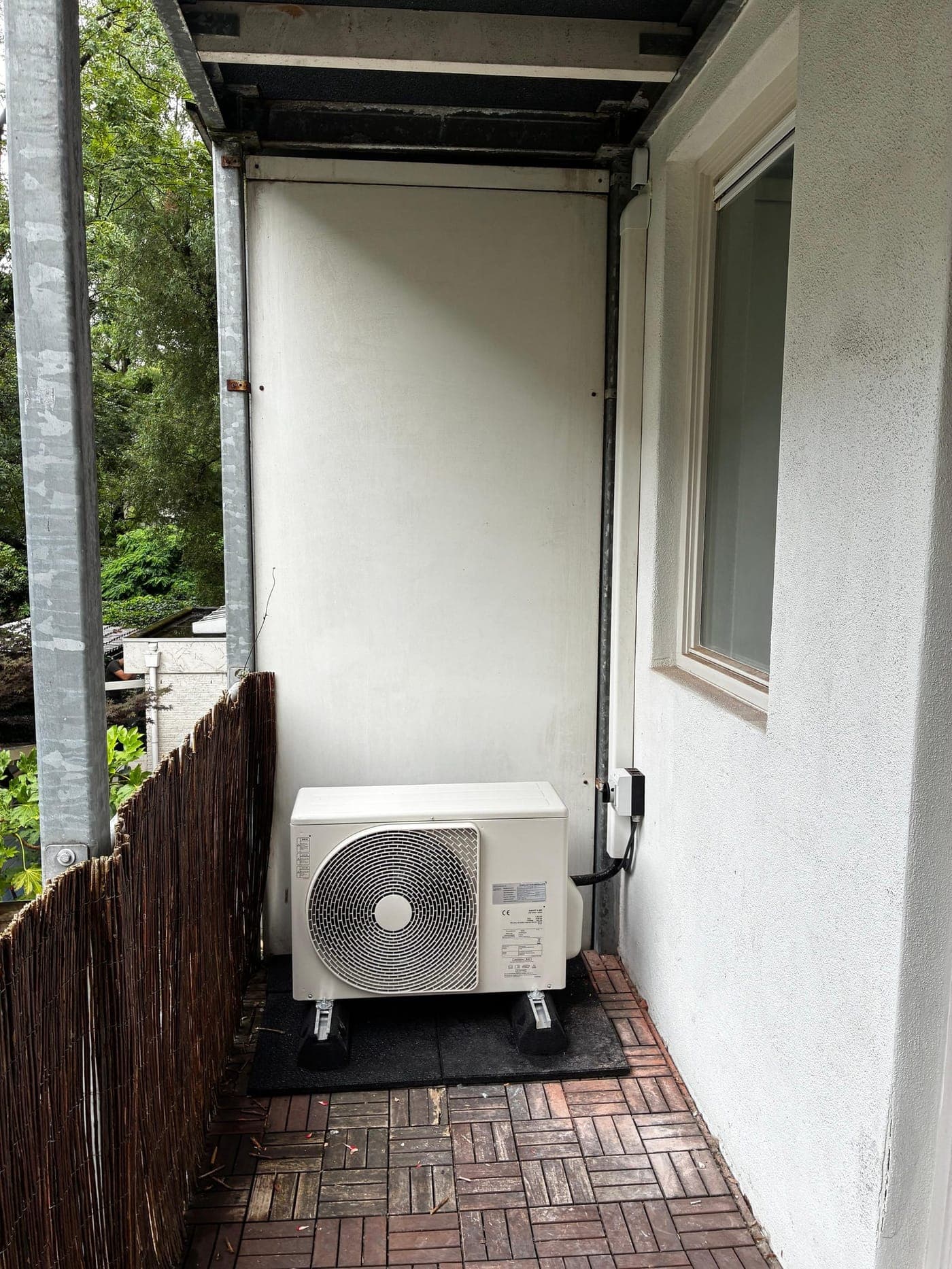 Buitenunit van een warmtepomp op trillingsdempers op een balkon